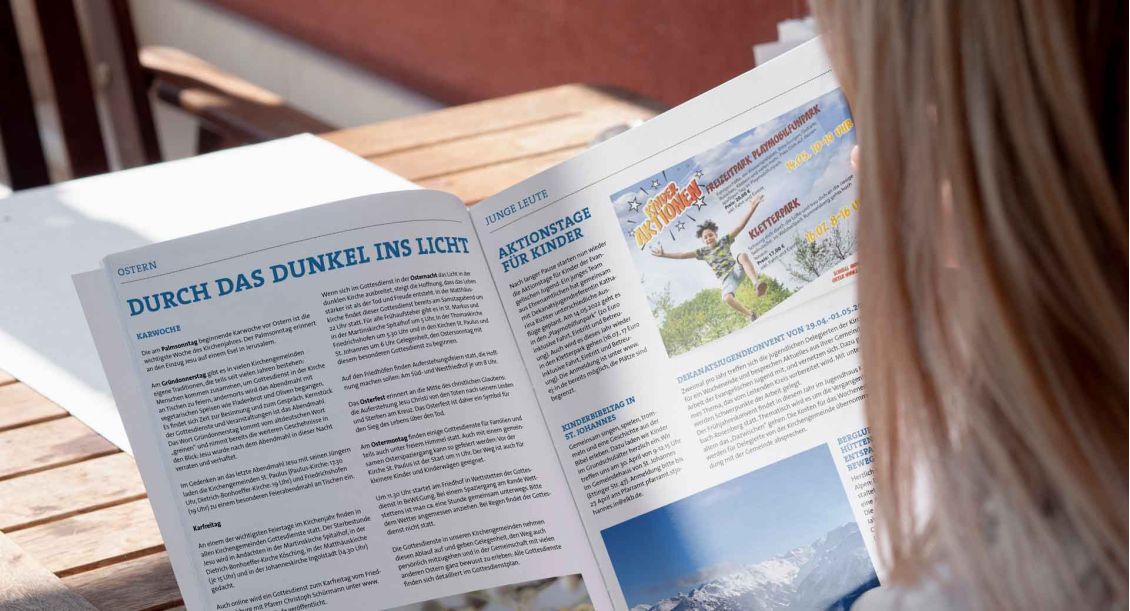 Eine Person blättert in der Dekanatszeitung "Der Monat"